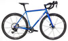 A blue Co-Motion Camino steel road bicycle with black components, drop handlebars, and carbon fiber wheels, shown from a side profile on a white background.